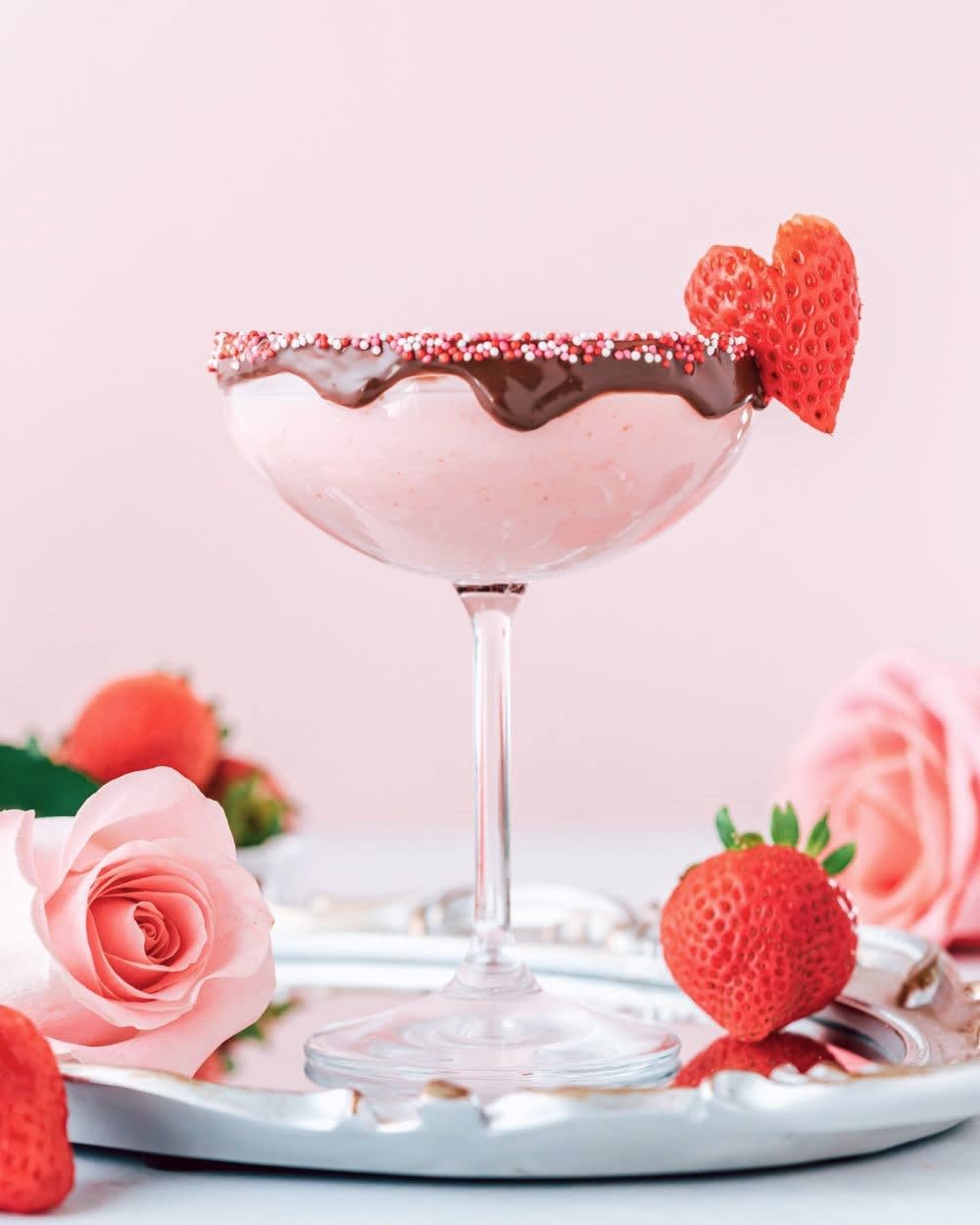 pink chocolate covered strawberry cocktail for valentine's day with white chocolate liqueur and magic shell rim