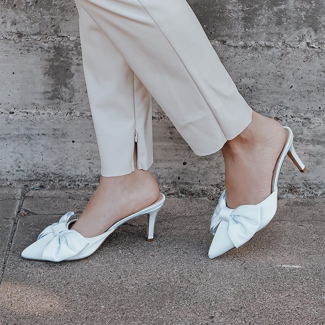 feet wearing light blue satin pointed toe mules
