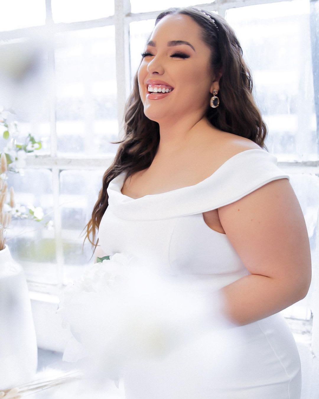 a woman in a plus size wedding dress holding flowers and smiling