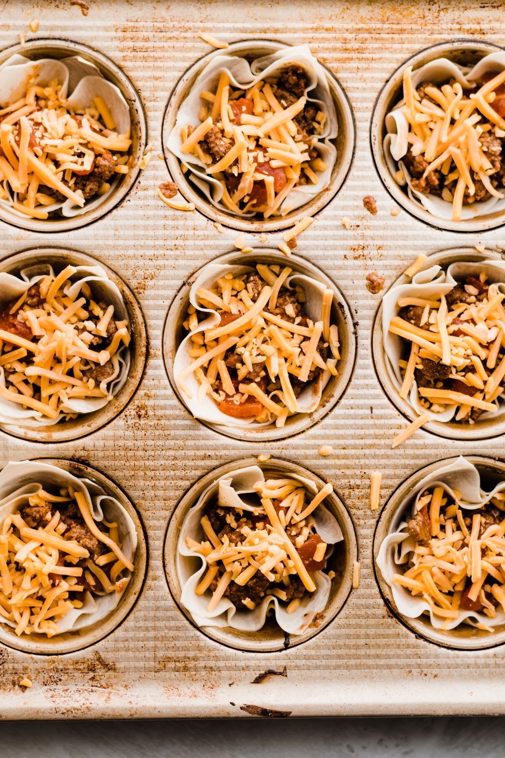 taco cups with meat, cheese and wonton in muffin tin