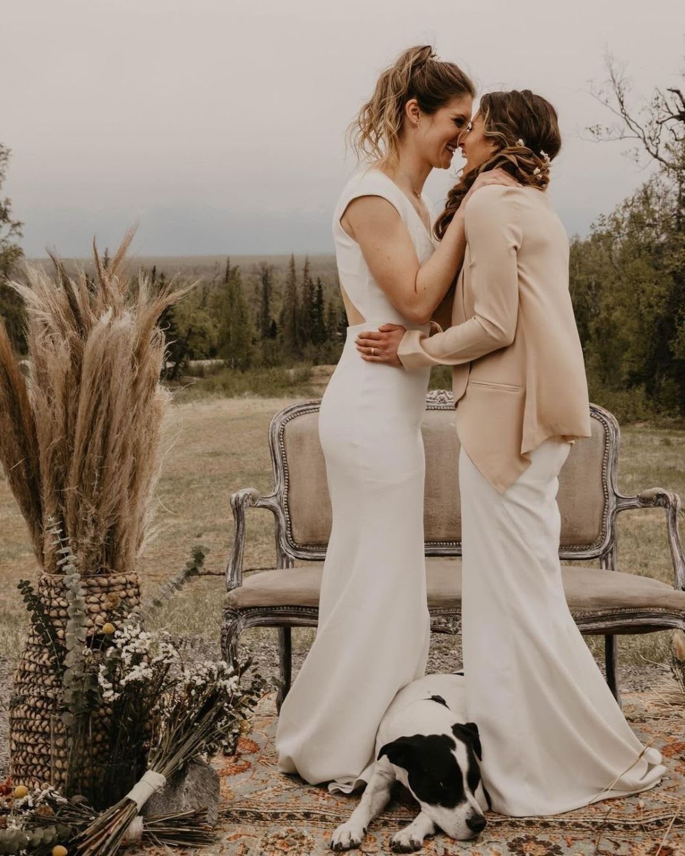 a bridal couple kisses in wedding dresses at an outdoor wedding