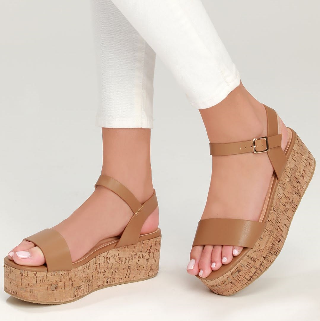 feet wearing brown wedge sandals with cork heels