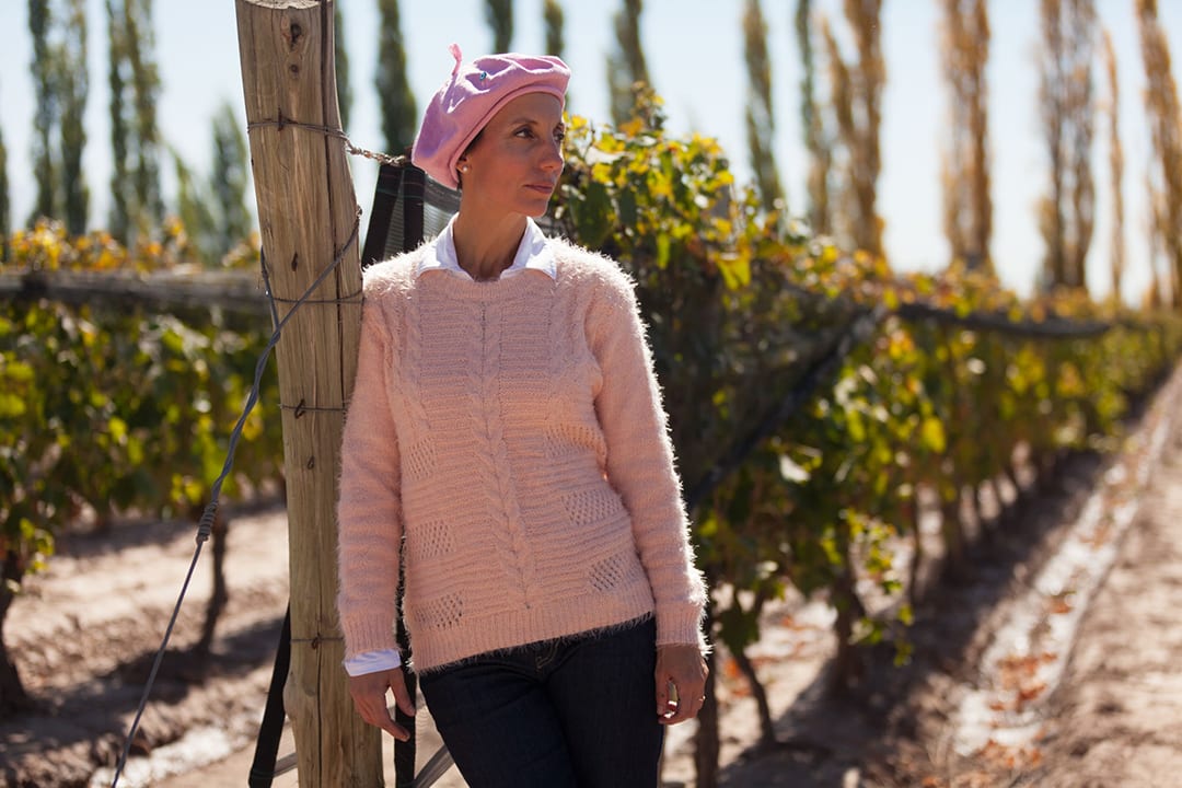 a photo of Jimena Lopez, female winemaker, in a pink sweater and beret,
