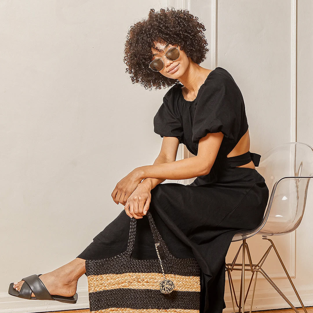 a model sitting on a chair wearing a black puff sleeve cutout maxi dress