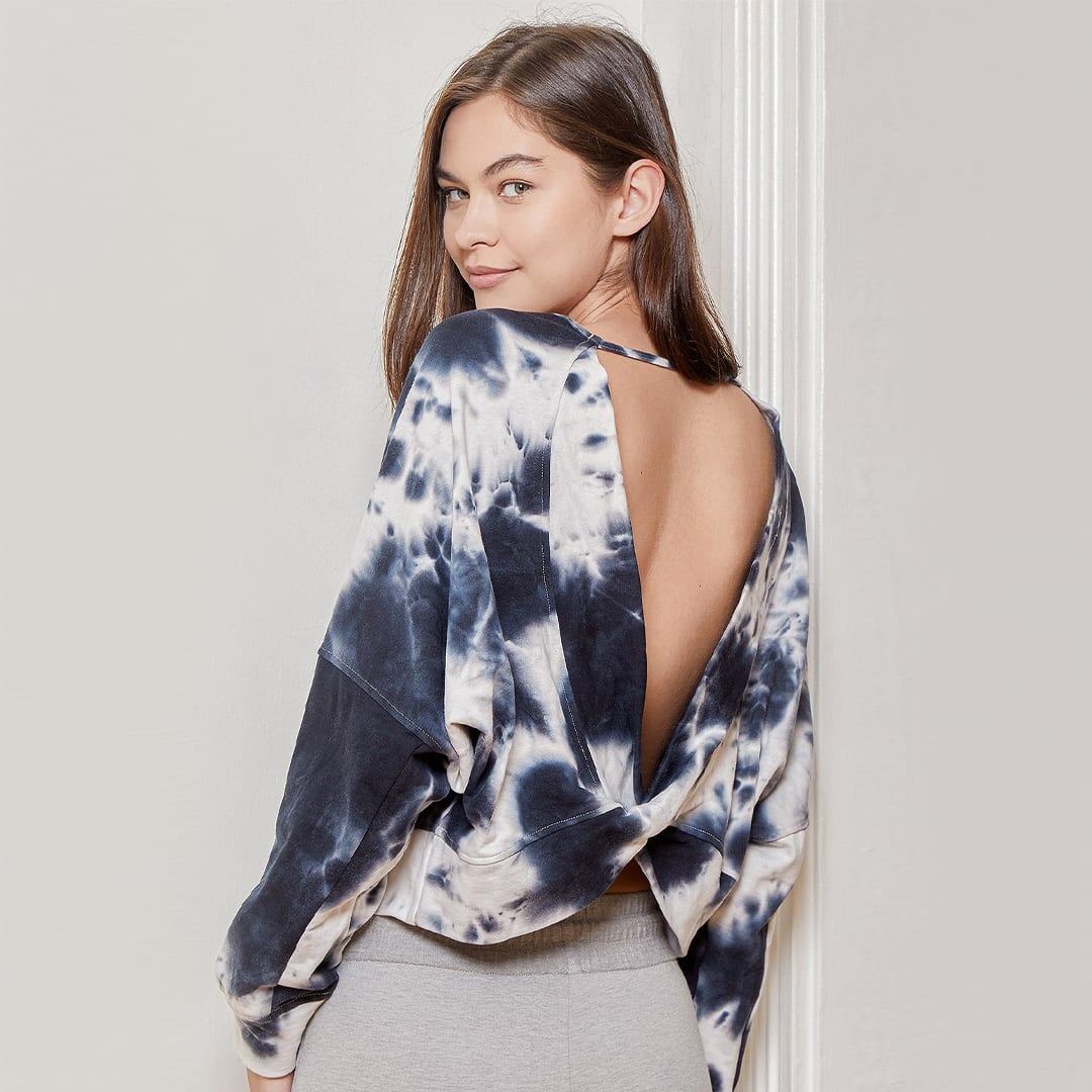 a model looking over her shoulder wearing a blue tie dye backless cropped sweater top