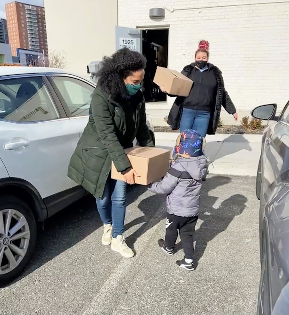 a woman handing mutual aid supplies to a child