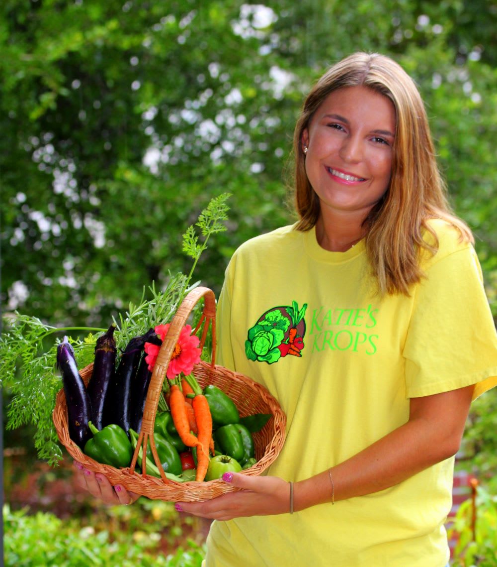 kate stagliano of katies krops holding a basket of fresh vegetables, as an example of women changing the world