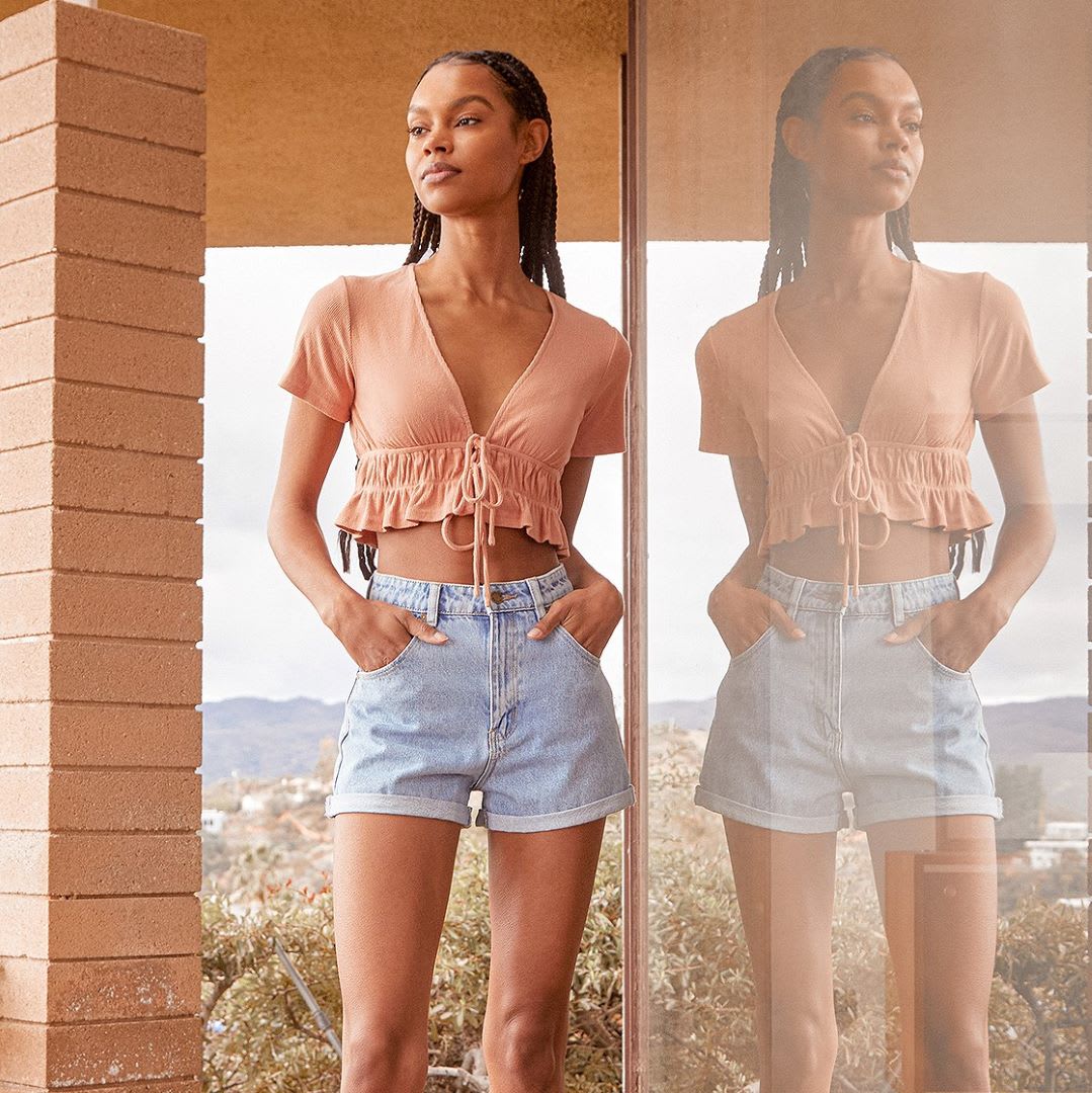 a woman in a peach crop top with denim shorts for a picnic outfit