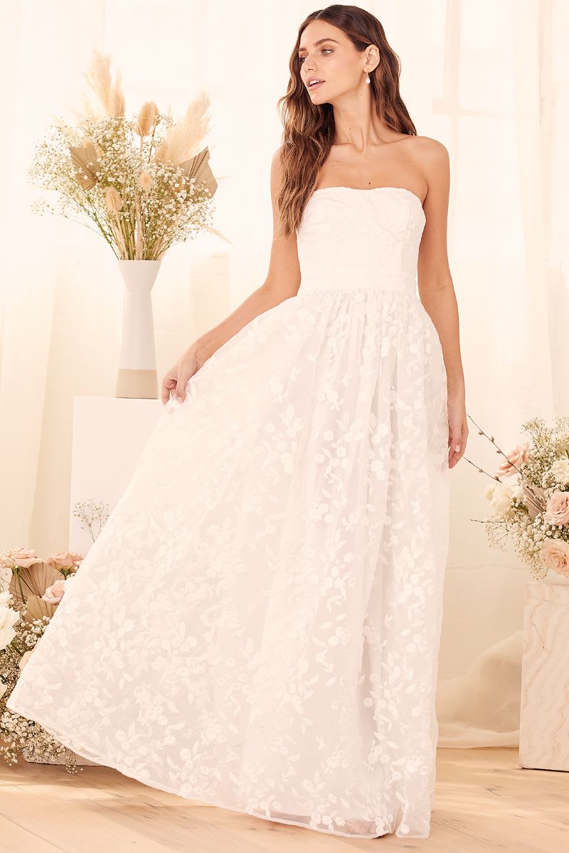 a model wearing a white strapless floral embroidered organza dress