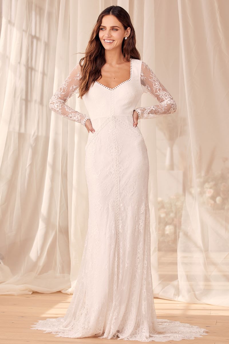 a woman with hands on her hips wearing a white lace backless long sleeve maxi dress from lulus weddings
