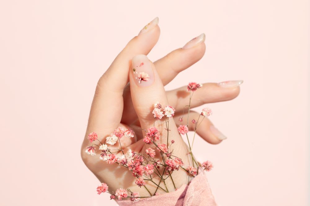 side view of a hand with dried flower nail art and babys breath peeking out of pink sleeve cuff