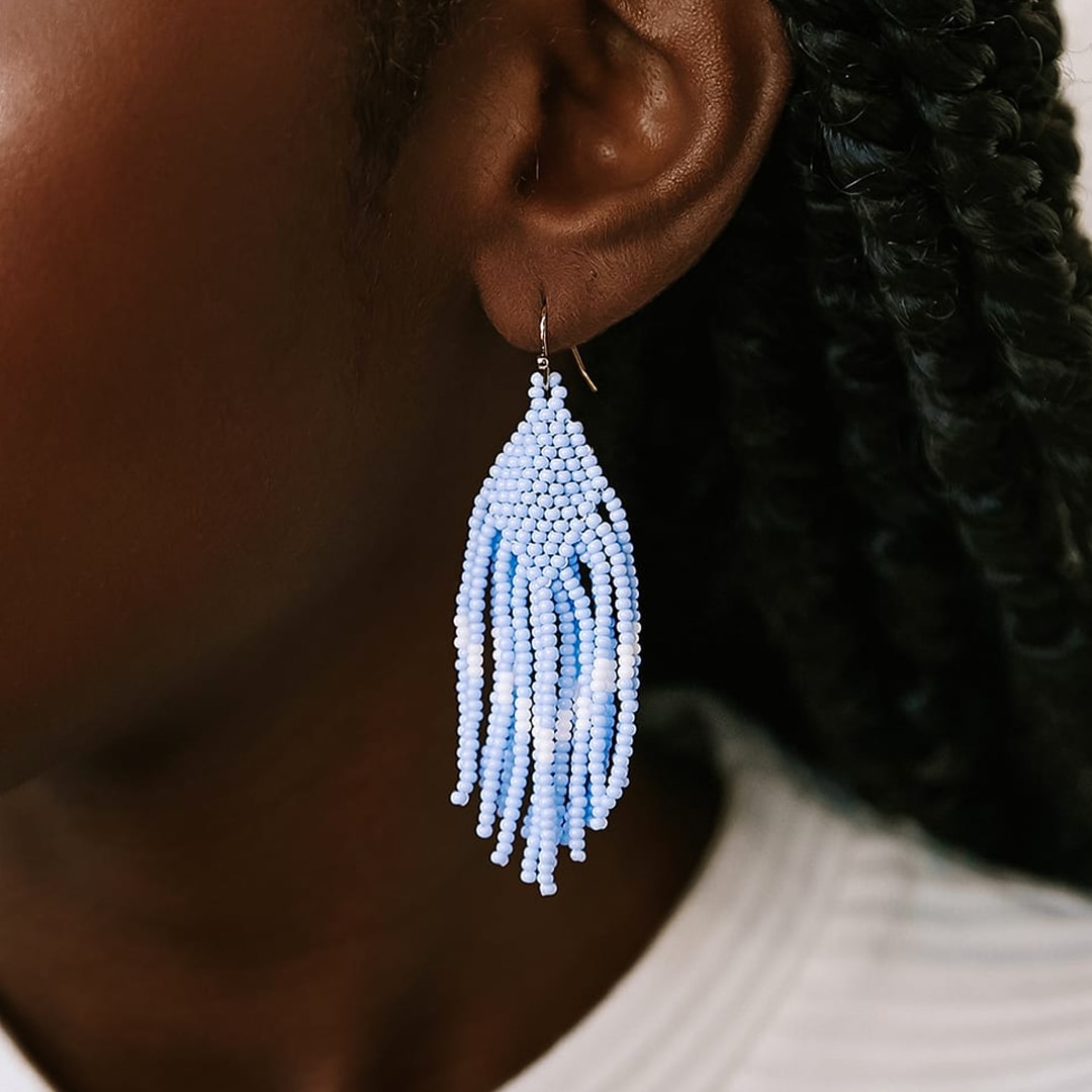blue and white beaded fringe earrings on a models ear