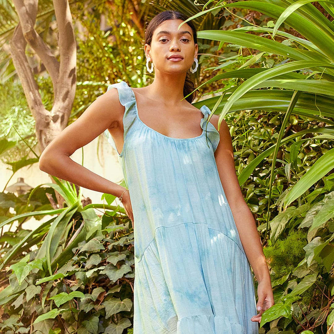 a model in front of leafy background wearing a blue tie dye midi dress