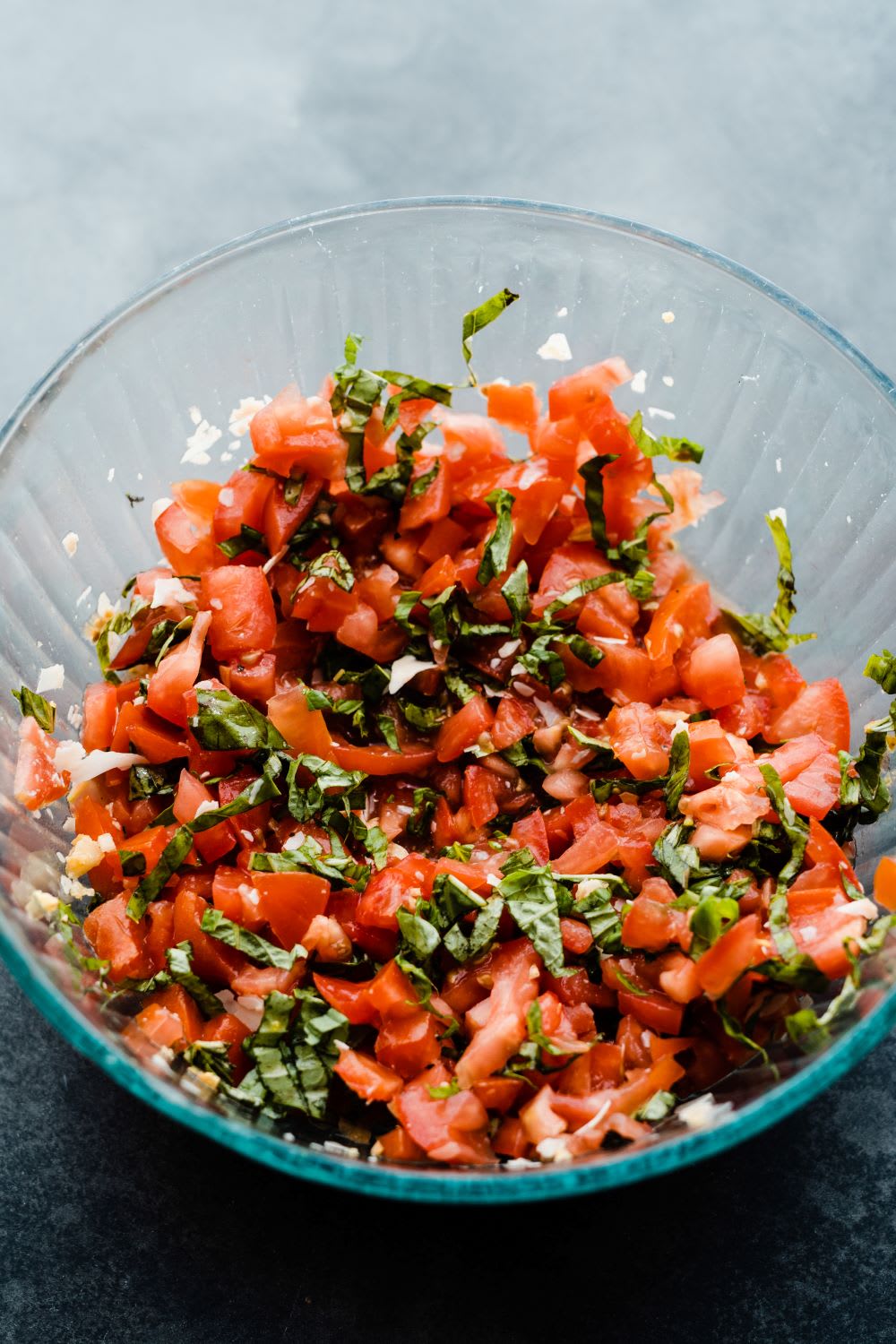 bruschetta appetizer recipe ingredients mixed together in a clear glass bowl