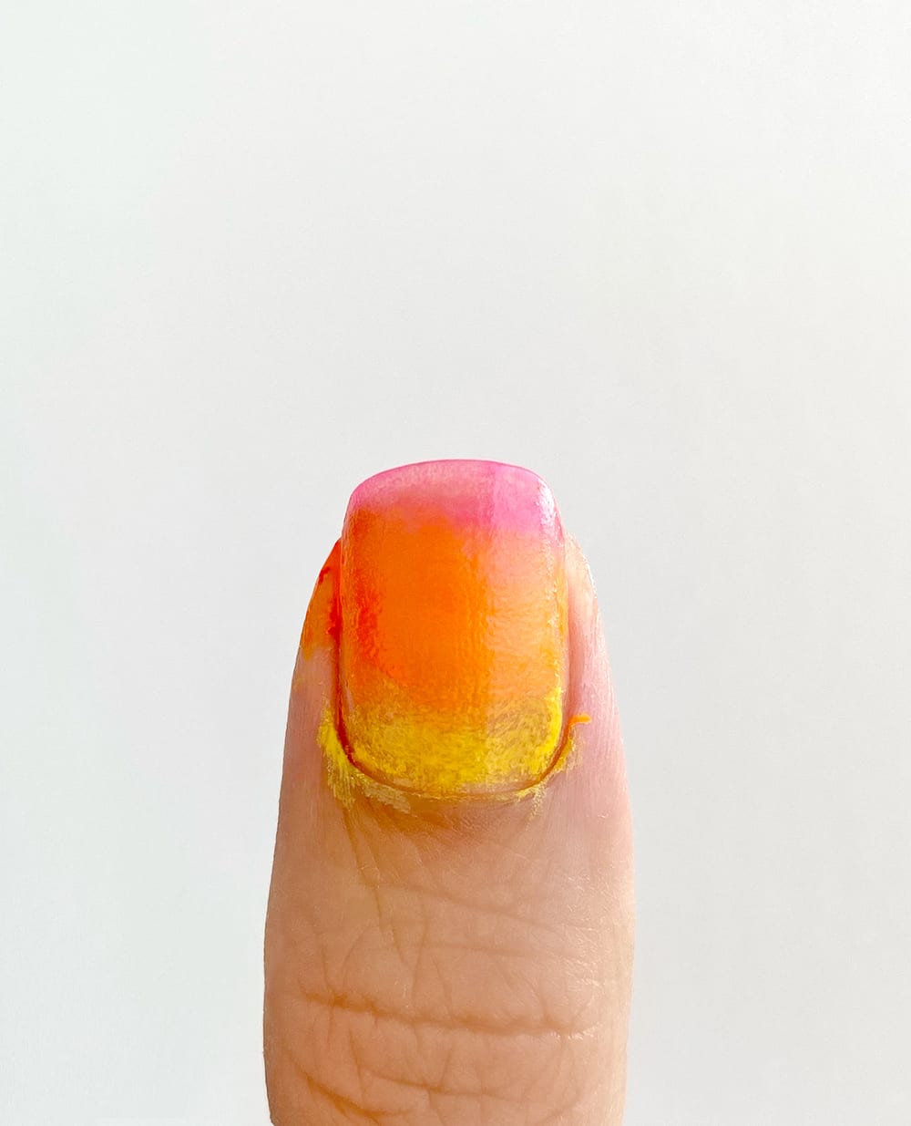 pink, orange, and yellow polish sponged onto nail