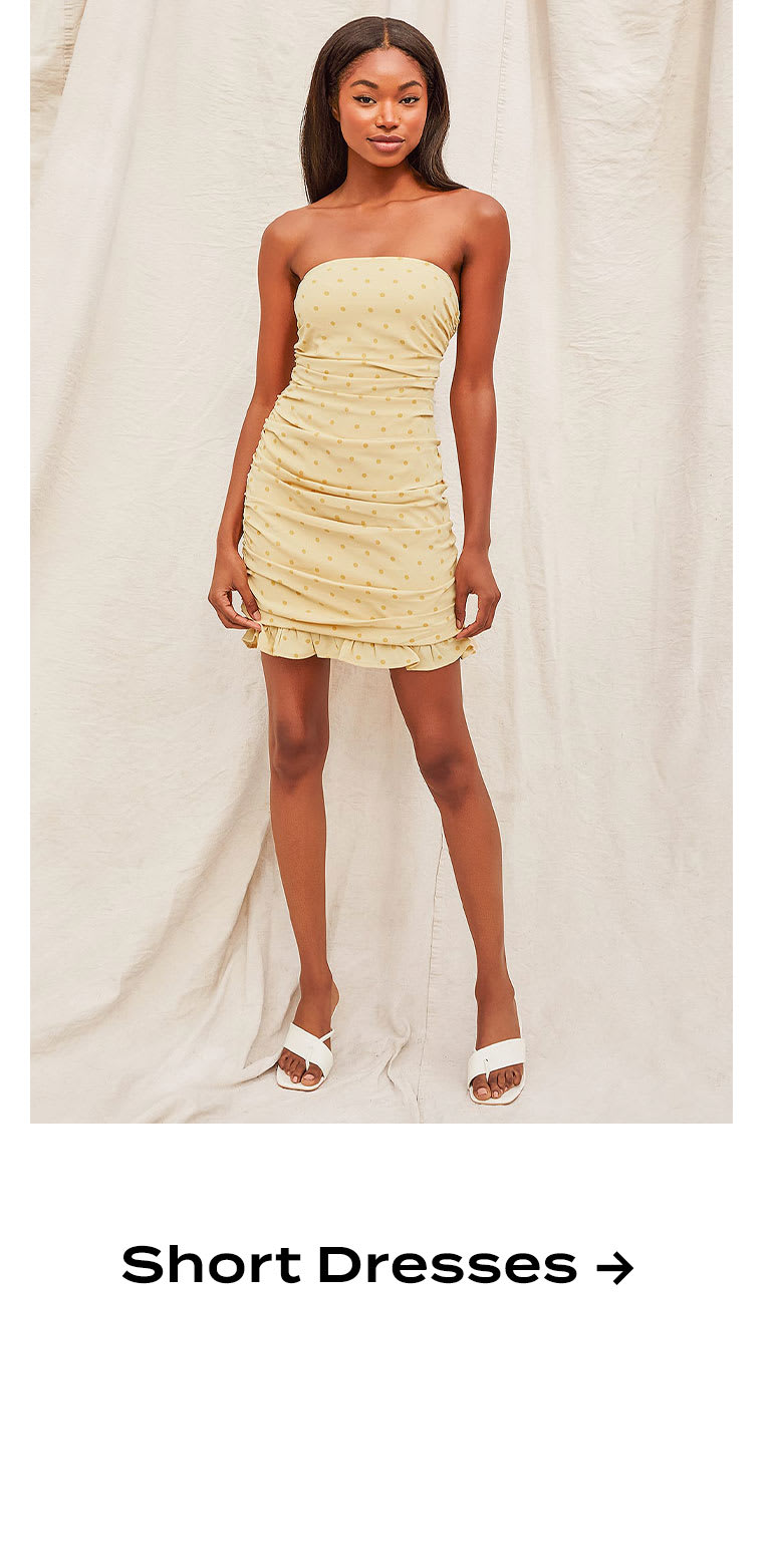 Model wearing yellow polka dot strapless mini dress