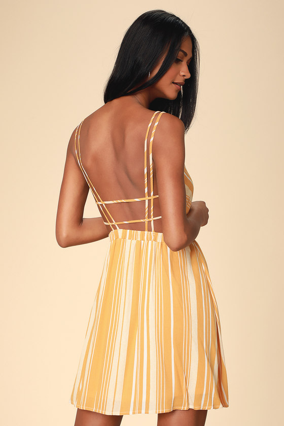 Oceanside Adventure Mustard Yellow Striped Backless Skater Dress - Lulus Exclusive! Spend the day searching for sea glass and starfish in the Lulus Oceanside Adventure Mustard Yellow Striped Backless Skater Dress! Mustard Yellow and white striped gauzy woven fabric swings from dual skinny straps, into a surplice bodice (with modesty stitch). Elasticized waist creates a comfy fit atop a perfectly breezy skater skirt. Strappy open back.