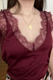 I got this top because I hoped the wide lace on the straps would allow me to wear a normal bra with it. It's true that my bra straps blended with the lace, however the v-neck was so low that I could plainly see much of my bra cups and the straps of the cami are non-adjustable due to the lace. This may not be as much of an issue for someone who is larger chested than I am, or if you don't wear a bra with the top. It's a shame because the color is gorgeous, it looks like a rich, purplish burgundy in person. Unfortunately, I'll be sending this one back. I also got Lulu's "Maddox Pale Pink Satin Lace Cami" which I like much more, and recommend you check out if you're on the fence about this one - Annie S.