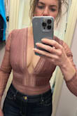 This bodysuit is so cute and very flattering. You don't need to wear a bra, just maybe nipple petals. I did return it just because at 44 I felt like I wouldn't have too many places to wear it. But if I went out more it would be perfect. I definitely didn't feel like I would fall out. It shows a lot but doesn't feel over snowy. The only thing that would make this better is if the textured part extended a little lower. You have to wear really high pants for the plain part to not show but it is the same color so looks okay if it does. - Cara D.