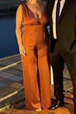 I wore this jumpsuit to a wedding in Cape Cod in late summer. It fit my large chest perfectly and I had a ton of compliments.
Definitely long (I wore 4 in heels and it still touched the ground by an inch) so I used iron on hemming tape to make it shorter and it was no issue at all. Ironed easily to get out wrinkles. Yes  the shoulder with the tie was longer but it was able to be tightened. I got a large because I didn't want it to be too tight on my bum and hips, I could have managed a M, but I'm glad I went with the L. Color is accurate, my photo just looks more orange, but it's more a rusty maroon - Elaine L.