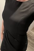 This dress is the perfect fit. It's form-fitting, doesn't have a lot of stretch and the material is on the heavier side, similar to a ponte knit. Not sure I would wear this to an outdoor summer wedding, but it would be great for a chillier day, in the Fall, or even in the Spring even if black is your go-to color! - Amie C.