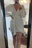 I bought this for my upcoming engagement party and it's exactly what I was hoping for. The pictures don't do it justice. If you have any curves, this hugs you in exactly the right places. It's a half wrap dress in that you don't actually wrap it yourself, it just looks like a wrap. There's a zipper on the side but the little ribbon belt is a true tie. It's definitely on the shorter side but it's double lined so you feel sucked in- perfect if your party is more of a cocktail event. For reference, I'm 5'4 athletic/curvy build 160 lbs and I bought a medium. Also, I'm wearing a strapless bra & it doesn't drop low enough to see it. - Kayleigh G.