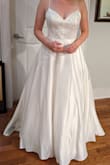 I have a month to change my mind lol but I think this is my dress. I've long been drawn to A-line and tulle princess styles but this just looked so much better on my body than any of the dresses with tulle skirts I tried. like to think this dress is the best of all worlds - it has the elegance of satin, the princess effect of a ball gown, a little romantic touch from the appliques... and yes, a touch of cleavage. I'm 5'5", 155 lbs, 32DDD, curves + lots of muscle. The 8 fits great - I think any looser and I'd need to have bra cups put in, tighter and I'd want to size up. Between the boning and big skirt, I think I might want a reception dress to change into after a while but I wouldn't say this is uncomfortable. I had it shortened in the front (not wearing heels) and will have the straps replaced - I don't think they look bad, but given the weight of my bust they dig into my shoulders when I move; I don't want red marks in the photos. (Pictured: the dress out of the bag + after hemming) - Christine F.