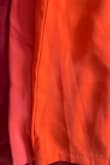 I bought this dress previously and LOVED it. It was bright orange and felt more expensive than it was. I needed to repurchase since it was a bit snug. First, I ordered a larger size and it was way too big, so I exchanged for the same size I already own. The straps are wider, the dress is longer and bigger (about two inches of extra fabric). The pleats on the straps aren't as nice, and the color is more of a dull red than bright orange like the previous one. So bummed because the original one was much nicer and it's too bad that customers will be swayed by sizing based on reviews of the older dress which ran small, comparatively with the new dress that runs big. New dress does have an added clasp to the zipper which is nice though. Wish Lulus would have made note of the new manufacturer/manufacturing process. - Caitlin F.