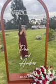 The red dress in these photos is absolutely stunning and perfect for a wedding! Its deep burgundy hue exudes elegance and sophistication, making it a standout choice for such a special occasion. The flowy tulle material adds a romantic and ethereal touch, while the plunging neckline and fitted waist highlight the figure beautifully without being overbearing.

The dress strikes a perfect balance between glamour and charm, ensuring it photographs beautifully in both indoor and outdoor settings. Whether seated or standing, the design and movement of the fabric make the wearer look effortlessly graceful. Paired with minimal accessories and natural makeup, this dress creates a timeless and memorable look. Truly an excellent choice for someone aiming to radiate confidence and elegance at a wedding! - Sarahi P.