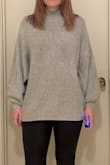 The material is really soft, softer than I expected, like a boucle consistency. VERY COZY like a blanket. The sweater is really cute on! I like the neckline, the sleeve cuffs, and how I can wear it long (hits a few inches below waist) or tuck it up for a more crop fitted look. The body is quite roomy as shown on the mode. It's a loose fit, but I would not go down a size. I ordered my typical size. Excited to wear it! - Katy M.
