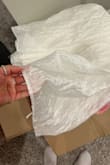 I purchased this dress and it does not look anything like the pictures. On top of that, the hooks where the strings go in completely came off when I tightened the dress. The material of the dress isn't a plain white it's almost iridescent like. Very disappointed - Jasmine M.