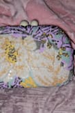 Am disappointed in the version I got. In the picture, it is mostly teal and bright colors with a little bit of the white flower. The one that arrived, the flower is in the center, so the bag is mostly white, and the black sequins that are just supposed to be an outline overwhelm any other colors, and the purple is more prominent than the teal. I guess each one is manufactured differently, but this is enough of a difference that I will probably end up donating it. - Katherine Z.