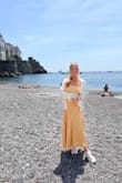 Fits true to size. Fabric does not stretch, and it zips at the waistband. Comfortable. I wear this dress with stick-on petals since the back is open, so bras with straps are not an option. Bought this to wear in Barcelona and the Amalfi Coast and it didn't disappoint. - Keara P.