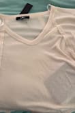 I'm sorry to say that I do not like this shirt. It looks so cute in the photos, but in person, not so much. The color is a bit darker, very cream, less off-white. The material has no structure or weight; it's thin, see through, and overall cheap looking. I would expect to buy this shirt for half the price that it is selling for.

As you can see in my photo, through the material, you can see the color of the blanket below, as well as the attached tag. - Lisa S.