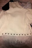 I received this sweater and it looked nothing like the one in the picture. The "rhinestones" which appear silver in the photo are actually bronze, and the fringe on the end was curled and sparse. I don't recommend. - Claire E.