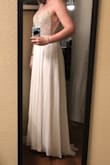 This dress is definitely more sparkly than I expected. It's really hard to take a photo to accurately depict this. It's also a little shorter than I thought it would be. Everyone (even tall girls) in the reviews kept going on and on about how long it was, but without shoes on, it barely brushes the floor. I think I can still get away with a modest heel (pictured wearing 3" heels), but I might just do flats. Overall, quality is great! I love the small train on the back and the multiple layers of flowy material on the bottom. The top is completely sheer, but luckily my skin tone is close to the color of the sewn in cups. Those with darker skin might have to put different cups in. Everyone I've shown it to so far thinks is gorgeous! I think I've found my wedding dress! - Kelsey H.