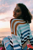 Ever since I saw this sweater 3 months ago I've been anxiously waiting for it to come back in stock!!!! I ordered the XS. The hem is curved inward, which threw me off at first, but it's actually really great because it gives the appearance that the sweater is tucked in. It doesn't look like it's just laying flat. It's a little shorter length-wise, but I would still buy in a heart beat. (Someone thought I was wearing a crop top when I was sitting.) the sleeves are bigger, as pictured, which make it super comfy and easy to throw on! It's the perfect weight for summer nights and windy days on the beach! - Chloe P.