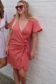 This dress fits true to size. It has a fairly soft material, be careful when washing (it will shrink). The only negative to this dress is that it shows a lot of cleavage. - Alexandra F.
