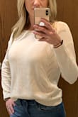 Cute sweater for fall/winter. Color is just as it appears online. It's a cream color with a subtle pink undertone. It does seem to wrinkle easily. I put my coat on for my ride to work and when I got to the office the front was bunched and wrinkled. Some of the wrinkles relaxed throughout the day but it was still wrinkly by the end of the day. Very soft material. Not at all itchy. - Mandi Y.