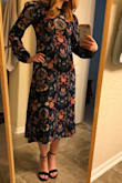 I've been waiting months for this to finally come back in a XS and I finally grabbed it. There was literally one dress left and it was an XS when I checked on it. Meant to be! Yay! I'd ordered this previously in my regular size small even though the reviews mentioned it running large. They weren't wrong. It fit, but it wasn't very flattering. I almost kept it anyway because I liked the dress so much but I'm glad I decided to return it and hope that an XS would come back in stock. The XS is PERFECT. Literally, zips right up and hugs me just right. There is no stretch in this fabric so it's a dream that it fits so well. The fitted waist makes it so flattering with the fluffier sleeves. The fabric isn't as expected, it almost has a crepe texture to it but it's fine. The colors are so vibrant and fun. It goes so well with my red hair. I can't wait to have a chance to wear it! - Jenna F.
