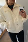 SIZE DOWN! I am usually a medium but I ordered a Small because of the other reviews and I'm glad I did! I have long arms so I was scared that the small size would have shorter sleeves and I'd look dumb but it actually goes over my past my wrists. It's very cozy, not so form-fitting but definitely will keep me warm. The color is a cute, neutral going on a soft yellow type, but it's cute. Would order again if they had black :( - Alizon P.