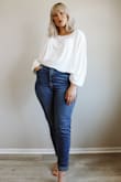 I wear this with extra high waisted jeans. I love the cropped fit (very cropped) and the huge flowy sleeves are my fave thing about this shirt! I got a Sz. Medium and I def could have gotten a Small but I loved the oversized/relaxed fit of this shirt. Very boho and I can wear with pretty much all of my high waisted bottoms. Love it and highly recommend if you don't like layering stuff under white shirts because it is not a see through material as long as you wear a nude bra underneath! I love wearing a white bralette underneath it to make it extra cozy. - Sarah K.