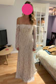 This dress is absolutely stunning. I purchased it for my wedding. There is so much attention to detail in its design. It's an elegant and delicate white lace atop a champagne underlay which gives the dress somewhat of a vintage feel, and makes the beautiful design of the lace pop. The off the shoulder sleeves fall perfectly and do not require any kind of ongoing adjustment with movement. There is beautiful lace detailing around the the neckline as well as a really pretty lace scalloping at the bottom of the skirt, which has a small, understated, but elegant train. The edges of the long sleeves are also scalloped, following the design of the lace. There are really pretty seams at the back on the skirt that make it fall and flow perfectly. I had planned on wearing a necklace with this dress, but I find the dress in and of itself to be so pretty and attention-grabbing that I no longer want to accessorize. It's a perfect dress for a winter wedding. I highly recommend it. - Meaghan G.