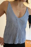 Would recommend ordering a size up if you want it to fit like the picture. I ordered a small, and it isn't as loose fiiting as the picture. The side strap is sewn into the side, so you cant adjust the tightness or height of that strap. It ties in the back but mostly just for show. The shirt is also shorter than I expected in the back. 
I washed it but hung it dry so it wouldn't shrink. Should have ordered a medium! - Tiffany S.