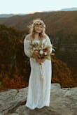 I got engaged in early 2019 & originally bought the "Flynn" dress from Lulus which is beautiful! Then Covid hit and plans changed & we landed on eloping in the mountains at the end of Oct. I had a moment a few weeks before the wedding that I maybe wanted a long sleeve dress & figured I'd give Lulus another shot. It's beautiful. I wasn't sure I would love the off-the-shoulder look as it's not something I generally go for but this ended up being the perfect dress for my mountainside elopement! So many compliments!

I still give it 5 stars, just something to consider when purchasing - the lace has no stretch/give, so if you have larger arms like me, I'd recommend sizing up and getting the dress itself taken in so you have arm movement. I probably could have gotten away with an MD if it weren't for the sleeves. The only other downside is the zipper on this one in comparison to the Flynn dress I bought is the zipper is not as good of quality and difficult to zip.

Photos - Hanna Wilson Photography - Tara S.