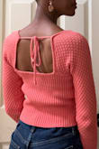 This sweater is such a warm vibrant salmon pink! The knit pattern on the sleeves and the tie on the back are so sweet! The hem hits right at the top of my belly button so I wear it with high-waisted pants. I wish they had a longer version! I bought it for cool days in the spring and summer - Stephanie S.