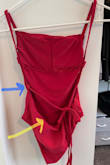 I was so excited to get this suit in the mail.  The material and color are beautiful and the fit is almost perfect.   The bottom loops for the drawstring are in the wrong place.  I requested an exchange for the same size but the replacement suit has the same issue.   The loops need to be farther down on the back seam.   The photos on your website show a beautiful tie in the back but the actual ties on the suits I received don't lay right.  I have attached two photos.  One from your website and one of the suits I received.   The blue arrows indicate the incorrect placement.  The yellow arrows indicate where the loops should be. - Kimberly G.