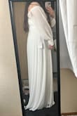 I have been nonstop searching for my wedding dress. I found this one and it was finally in stock, ordered and prayed it would look just like the photo and my prayers were answered. It's long and flowy, the button detailing on the sleeve cuffs is beautiful and overall fits snuggly and hugs all the right curves. The fabric itself is nice but a little see-through, so I'll probably wear something white underneath. I do wish the sleeves were a little longer so I can wear the sleeves on my shoulders instead of the off-the-shoulder look but overall I am so happy with it! - Maria G.