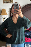The material feels thin but still of good quality. The color is more teal than emerald green. The back is a bit longer than the front so that feels nice, it gives the sweater a cozier feeling. The cuffs are tight but in a good way, so cold wind won't come up to your arms. I loved it. I'll definitely get it in a different color. - Amparo C.