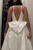 This was a return for me, but only because it didn't flatter my body or match the vibe of my event (wedding). Upon seeing the dress, the bow, leg slit, and the low back was my favorite thing about this dress, but everything else didn't work out for me. There was too much tule for my liking and it was very noisy when walking. The bow is detachable (by two simple buttons) and considerably lighter when removed. It was very easy to remove which made me nervous. The slit was... How do you say? "Not giving." I am smaller chested and the top of the dress was a little large, but not large enough that I should size down. The straps are adjustable, but not totally. The strap widens as it gets to the top of the shoulder, so it makes the straps look odd as the adjustable piece gets closer to the top. I saw the other reviews and they looked lovely and beautiful. It just didn't work out for me. - Chelsea K.